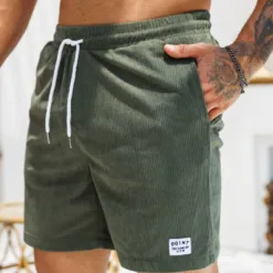 A close-up of a man wearing olive green men's corduroy shorts with a white drawstring.