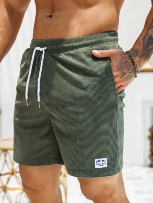 A close-up of a man wearing olive green men's corduroy shorts with a white drawstring.