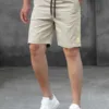 A man wearing a pair of beige men's tech shorts with a black drawstring.