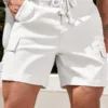 A man wearing a pair of slim fit white men's cargo shorts with a thick braided drawstring.
