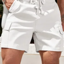 A man wearing a pair of slim fit white men's cargo shorts with a thick braided drawstring.