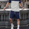 A man wearing a modern navy and grey color-block men's tracksuit.