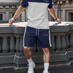 A man wearing a modern navy and grey color-block men's tracksuit.