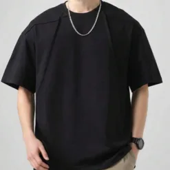 A man wearing a black men's oversize t-shirt with unique seam detailing.