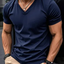 A man with a muscular build wearing a navy blue slim fit men's V-neck t-shirt.