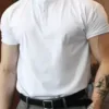 A man wearing a white slim fit men's Henley shirt with grey trousers.