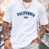 A man wearing a white oversize California t-shirt in a classic collegiate font.